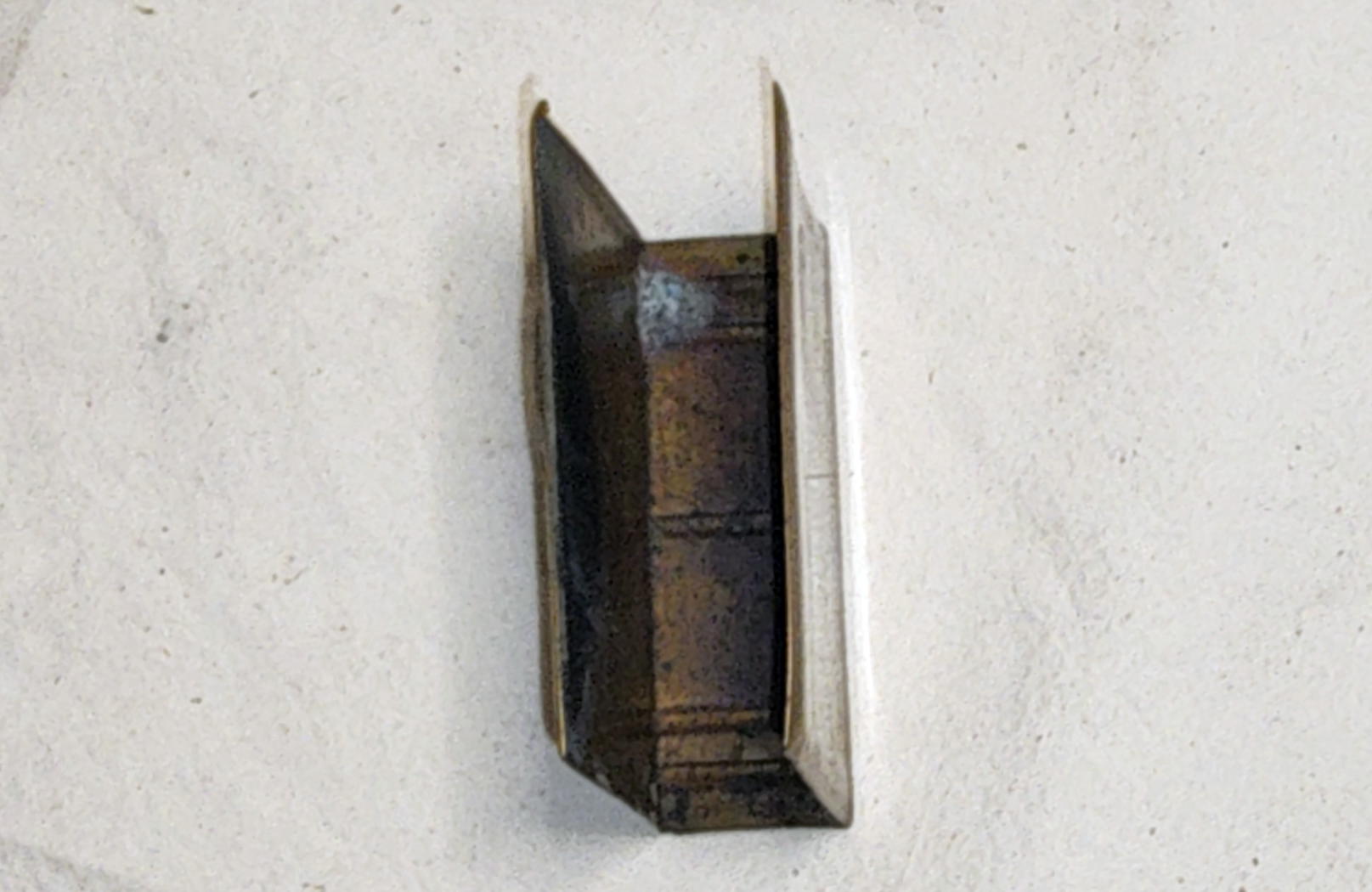 Open side of the empty brass matchbox holder showing the folded body and interior