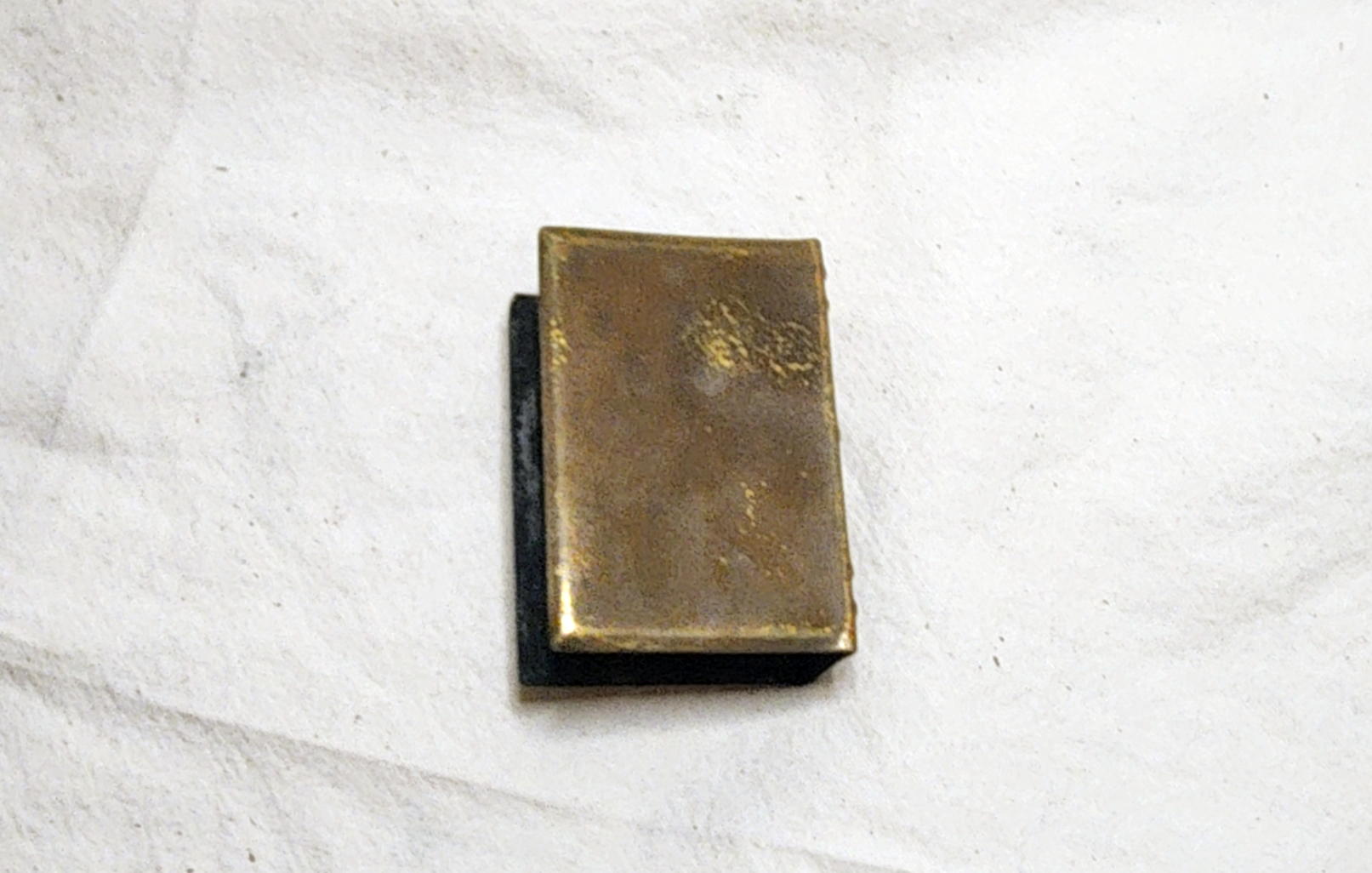 Plain reverse of the brass matchbox holder with surface wear and scratches