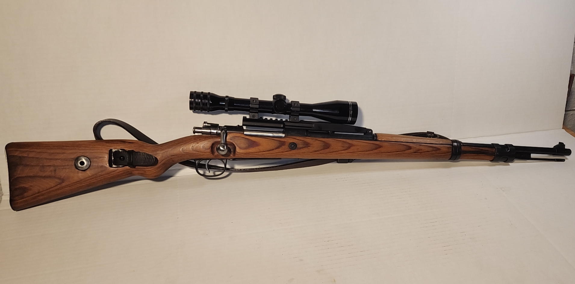 Overall left-side view of the Mauser K98k showing bolt, scope, and stock profile