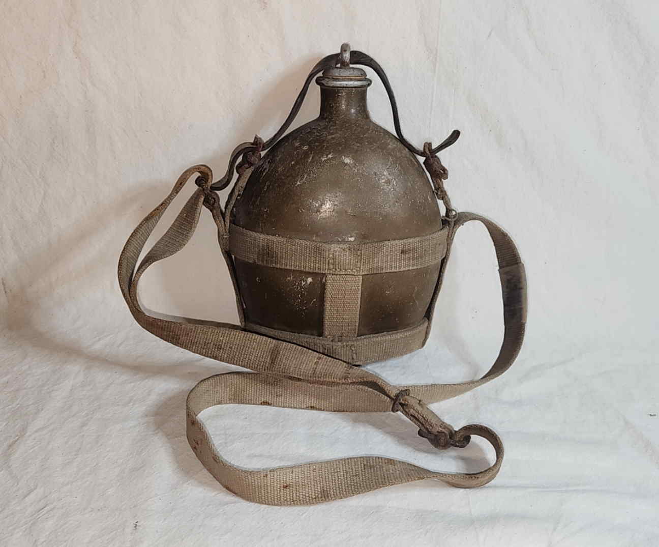 Front view of a 1940 Imperial Japanese Army Sho-5 I-go canteen with cotton web carrier and leather stopper strap