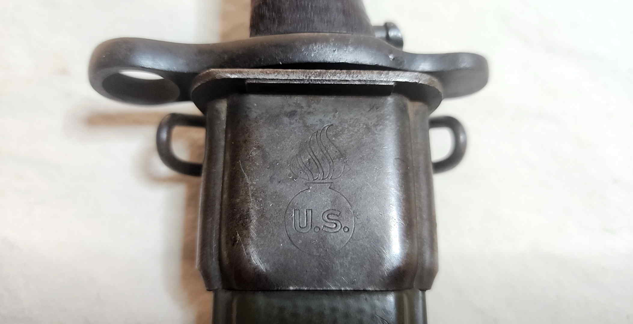 Steel throat of the fiberglass scabbard marked with the U.S. Ordnance shell-and-flame emblem